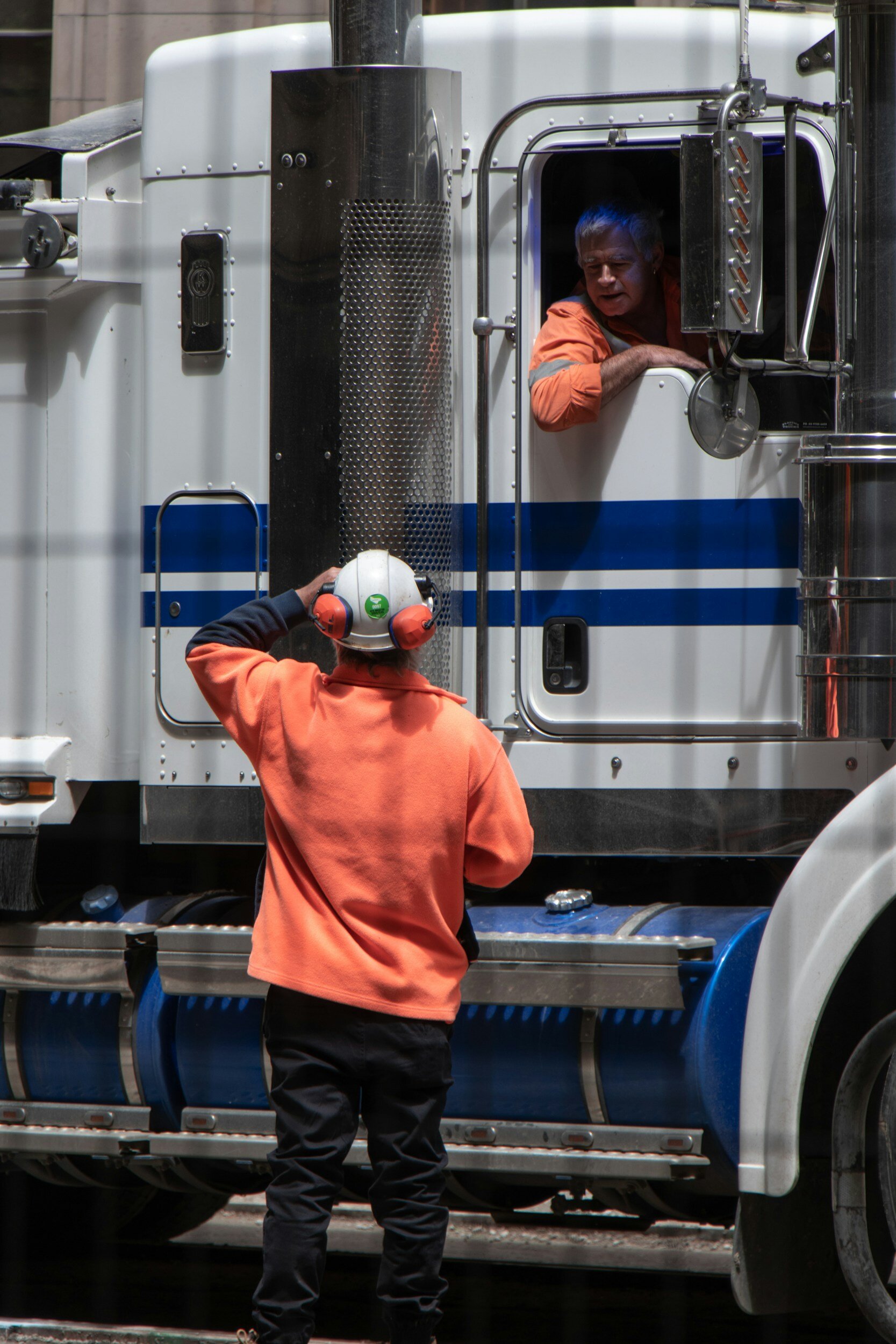 Two Truck Drivers conversing inside and outside a Semi Truck