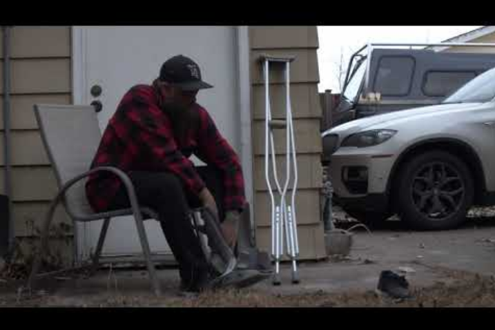 Injured person wearing a cast sits down beside crutches