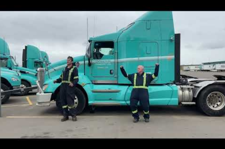 Two drivers in front of a turquoise semi truck