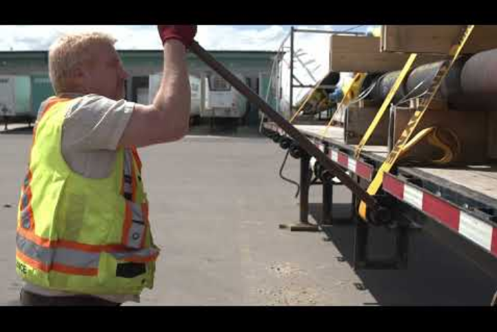 truck driver securing cargo on a truck bed