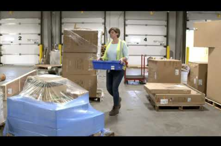 Warehouse employee carrying a blue bin