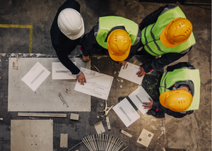 Birds-eye view of a group of construction workers looking over documents