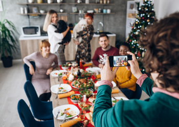 Person using a smartphone to take a photo of their colleagues at an office Christmas dinner party